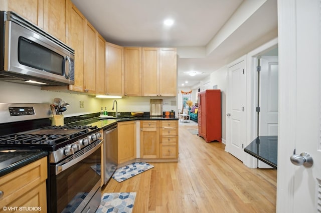 kitchen with stainless steel appliances, light brown cabinetry, sink, and light wood-type flooring