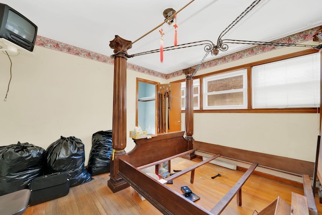 bedroom featuring decorative columns and wood-type flooring