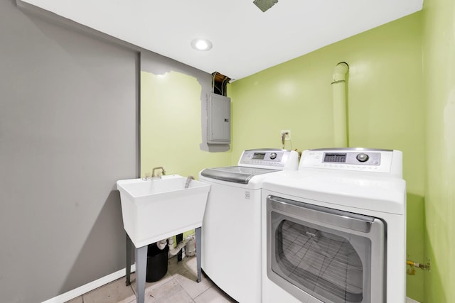 laundry room featuring electric panel, washing machine and dryer, and light tile patterned floors