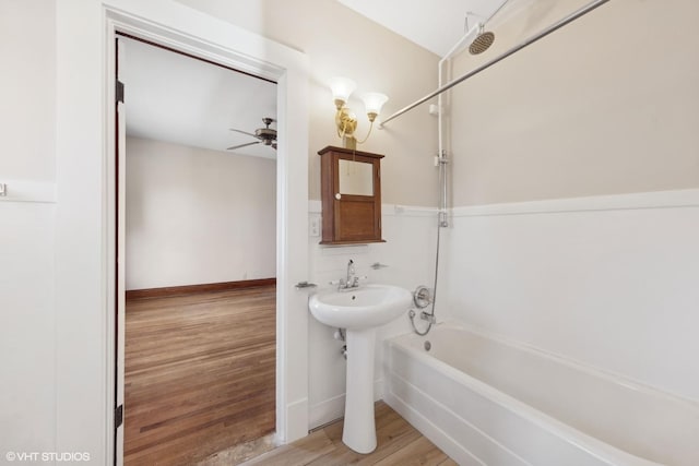 bathroom featuring hardwood / wood-style flooring, ceiling fan, and washtub / shower combination