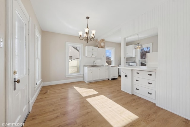 kitchen with white cabinets, hanging light fixtures, white appliances, an inviting chandelier, and light hardwood / wood-style flooring