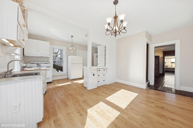 kitchen featuring white cabinetry, hanging light fixtures, white appliances, and sink