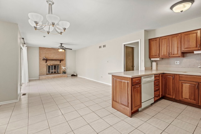 kitchen with pendant lighting, dishwasher, a fireplace, ceiling fan with notable chandelier, and kitchen peninsula