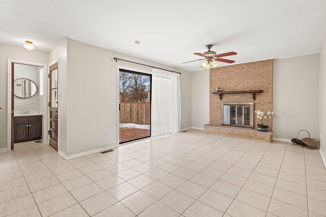 unfurnished living room with light tile patterned flooring, ceiling fan, and a brick fireplace