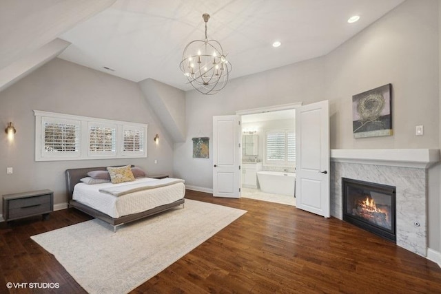 bedroom featuring an inviting chandelier, connected bathroom, dark hardwood / wood-style flooring, and high vaulted ceiling