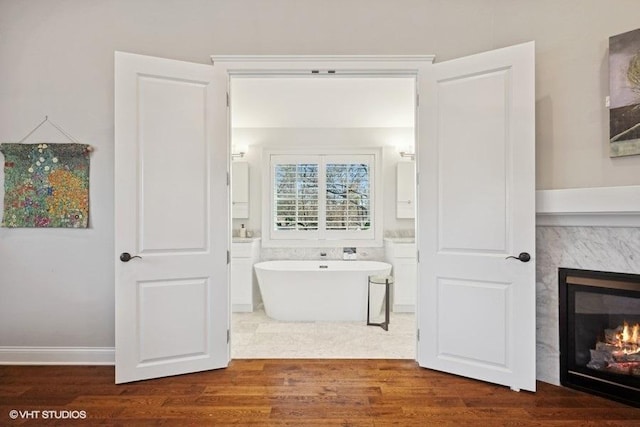 bathroom with wood-type flooring, a high end fireplace, and a bathtub