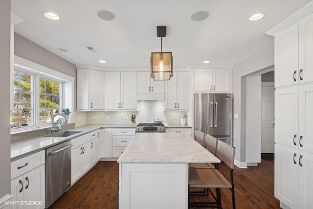 kitchen with a kitchen island, appliances with stainless steel finishes, decorative light fixtures, sink, and white cabinets