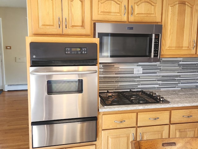 kitchen featuring a baseboard heating unit, backsplash, dark hardwood / wood-style floors, and appliances with stainless steel finishes