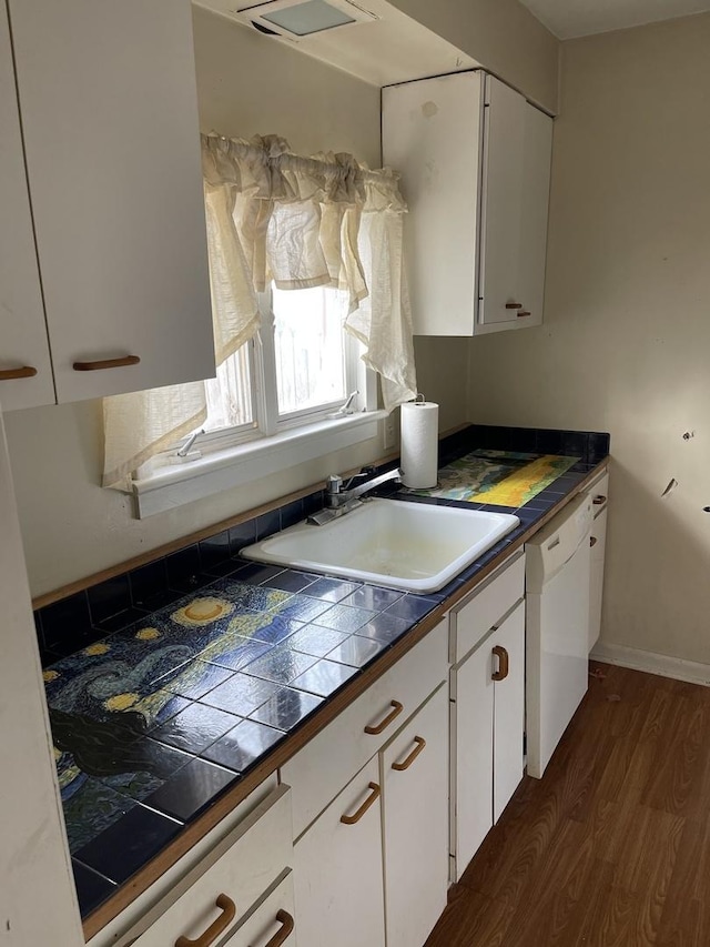 kitchen with dishwasher, white cabinetry, sink, and tile countertops