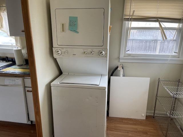 laundry room with stacked washing maching and dryer and dark hardwood / wood-style flooring