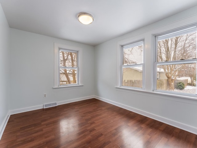 unfurnished room featuring dark wood-type flooring and a wealth of natural light