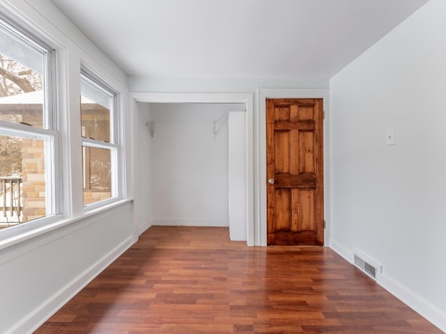 unfurnished room with a healthy amount of sunlight and dark hardwood / wood-style flooring