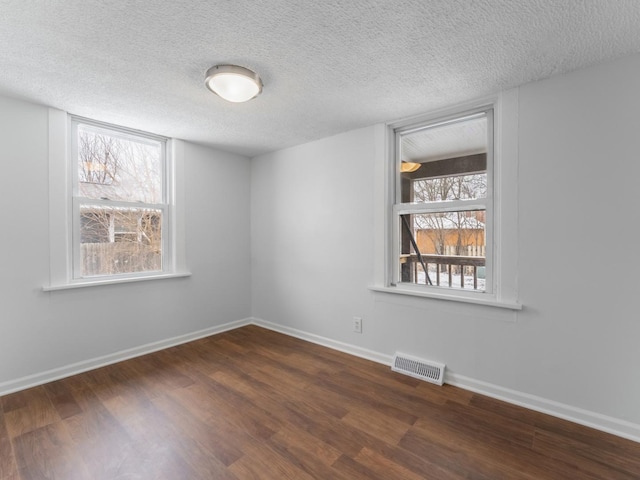 unfurnished room with plenty of natural light, dark hardwood / wood-style floors, and a textured ceiling