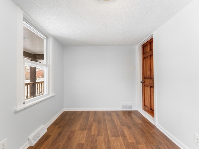 unfurnished room with dark wood-type flooring and a textured ceiling