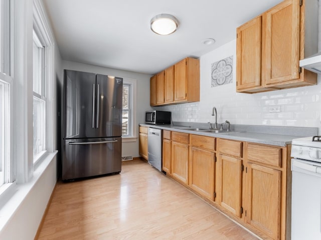 kitchen featuring light brown cabinetry, sink, decorative backsplash, stainless steel appliances, and light hardwood / wood-style flooring