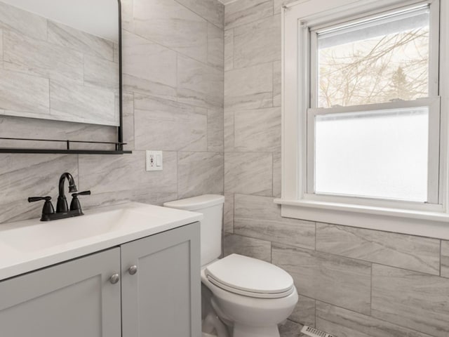 bathroom with vanity, toilet, and tile walls