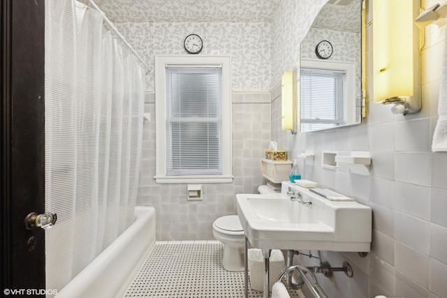 full bathroom featuring toilet, sink, tile walls, and shower / bath combo