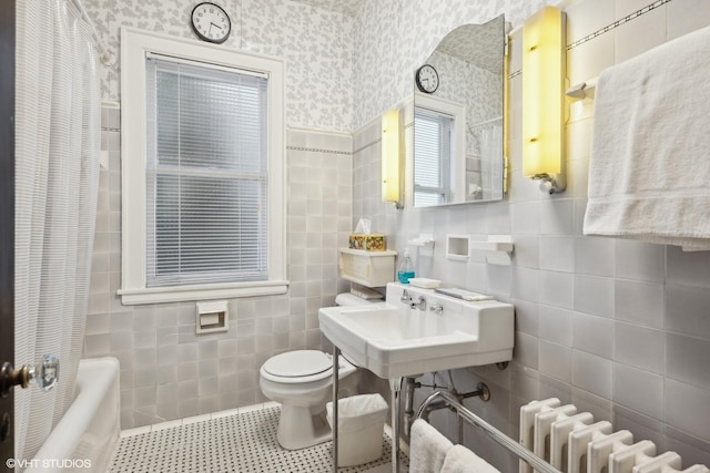 bathroom featuring radiator heating unit, toilet, separate shower and tub, and tile walls