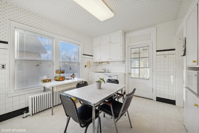 dining area featuring radiator, sink, and tile walls