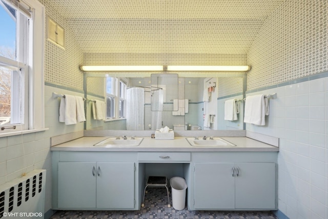 bathroom with vanity, radiator, and tile walls