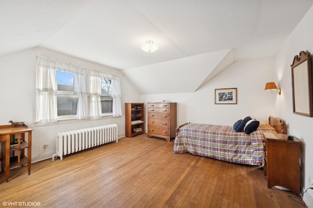 bedroom featuring wood-type flooring, lofted ceiling, and radiator heating unit