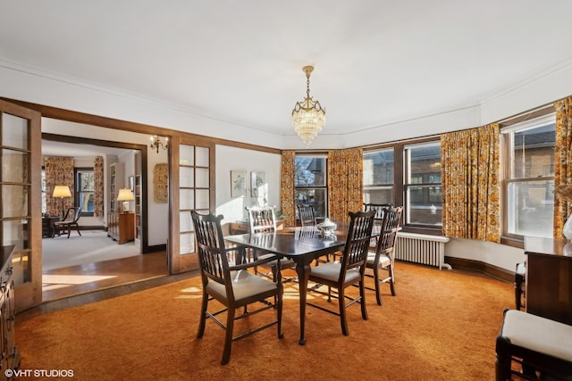 unfurnished dining area with an inviting chandelier, radiator heating unit, crown molding, and carpet floors