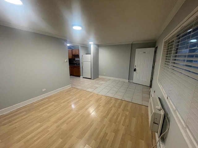 unfurnished living room featuring crown molding, a wall unit AC, and light hardwood / wood-style floors