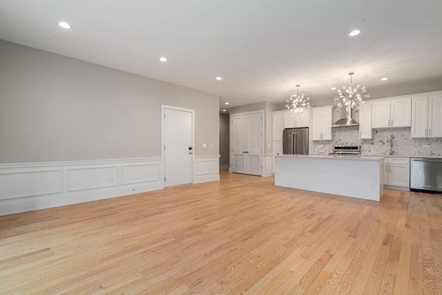 kitchen featuring appliances with stainless steel finishes, a center island, white cabinets, decorative light fixtures, and a chandelier