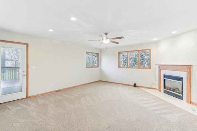 unfurnished living room with light carpet, a tiled fireplace, and ceiling fan