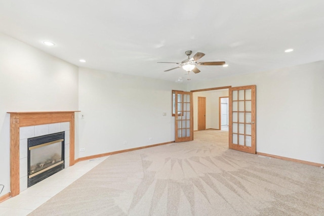 unfurnished living room featuring french doors, ceiling fan, light carpet, and a tile fireplace