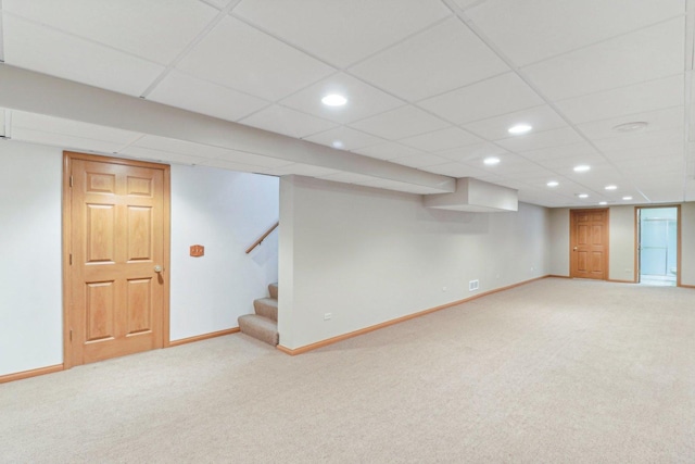 basement featuring a drop ceiling and carpet