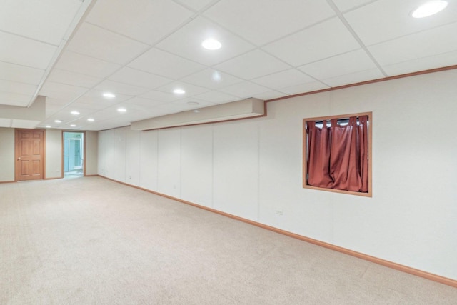 basement featuring a paneled ceiling and light colored carpet