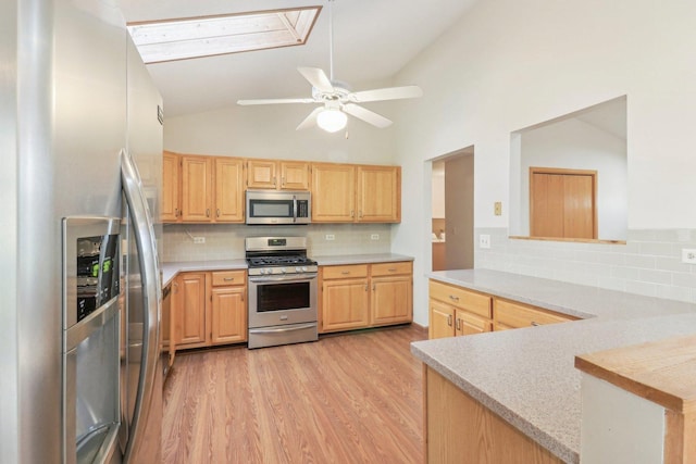 kitchen featuring lofted ceiling, ceiling fan, stainless steel appliances, light brown cabinets, and light hardwood / wood-style flooring