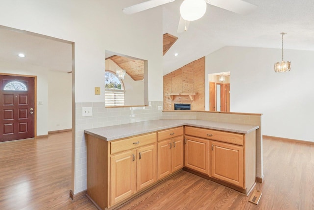 kitchen featuring lofted ceiling, light wood-type flooring, and kitchen peninsula