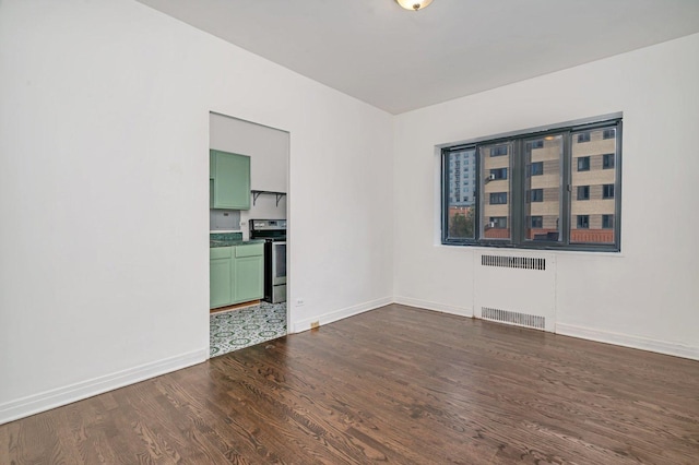 empty room with dark wood-type flooring and radiator heating unit