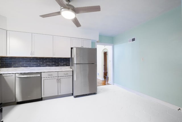 kitchen featuring stainless steel appliances, white cabinets, ceiling fan, and decorative backsplash