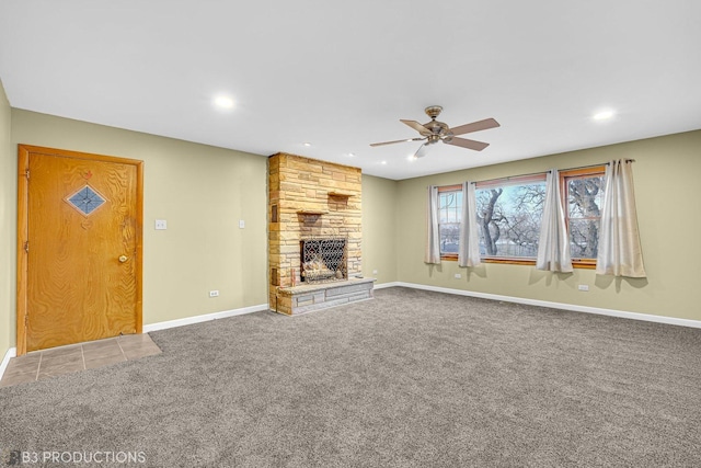 unfurnished living room with a stone fireplace, ceiling fan, and carpet