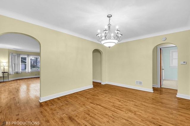 unfurnished room featuring hardwood / wood-style floors and a chandelier