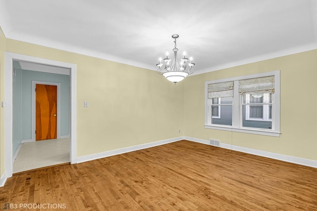 spare room with hardwood / wood-style flooring and a chandelier