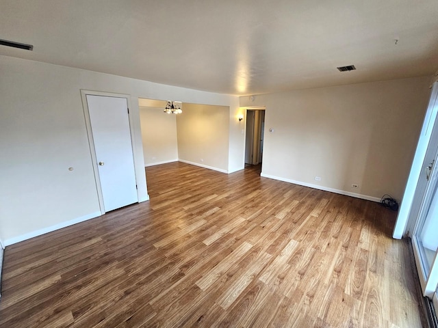 unfurnished room featuring a notable chandelier and light hardwood / wood-style flooring