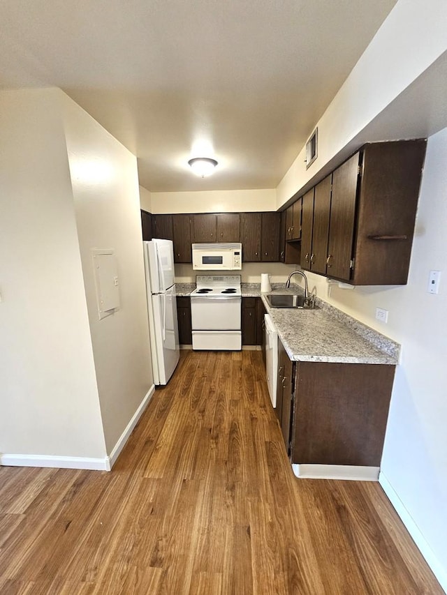 kitchen featuring white appliances, dark brown cabinetry, dark hardwood / wood-style flooring, and sink