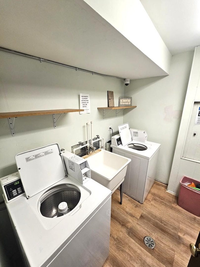 washroom with wood-type flooring, sink, and washing machine and clothes dryer