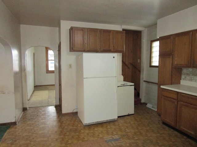 kitchen with white refrigerator, light parquet flooring, a wealth of natural light, and backsplash