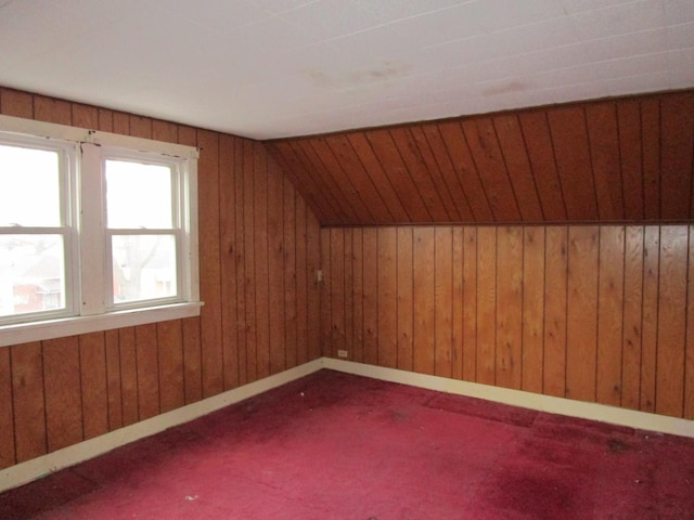 bonus room featuring carpet floors, vaulted ceiling, and wooden walls