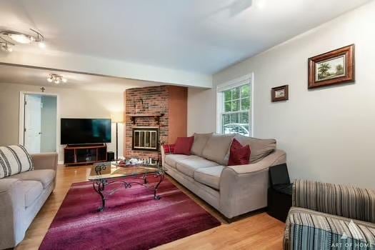 living room featuring a brick fireplace and light wood-type flooring