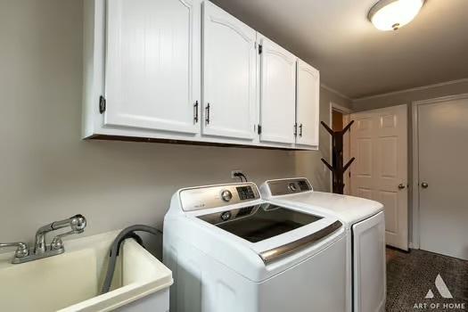 clothes washing area featuring cabinets, washing machine and dryer, and sink