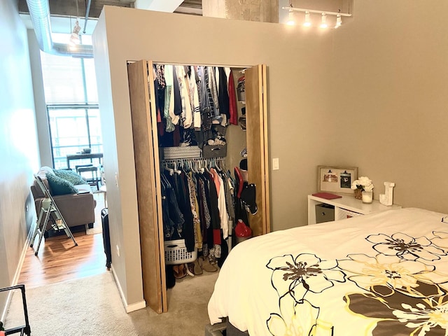 bedroom with light carpet, track lighting, and a closet