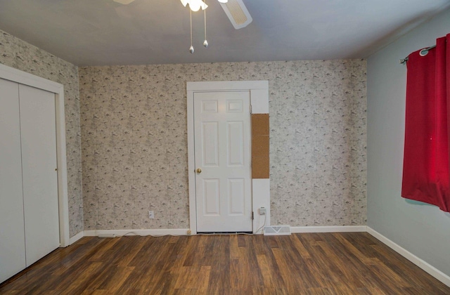 unfurnished room featuring wood finished floors, a ceiling fan, baseboards, visible vents, and wallpapered walls