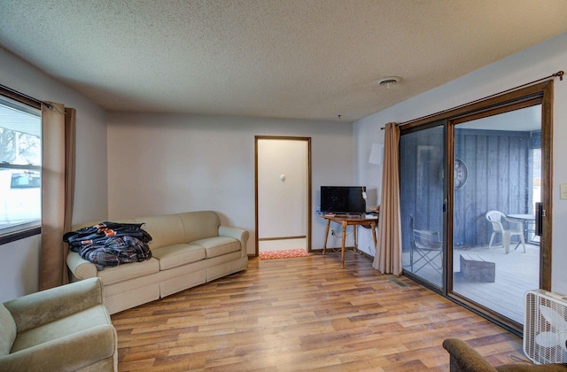 living room featuring light wood-style floors, visible vents, and a textured ceiling