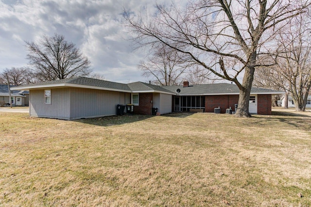 rear view of house with a chimney, a lawn, and brick siding